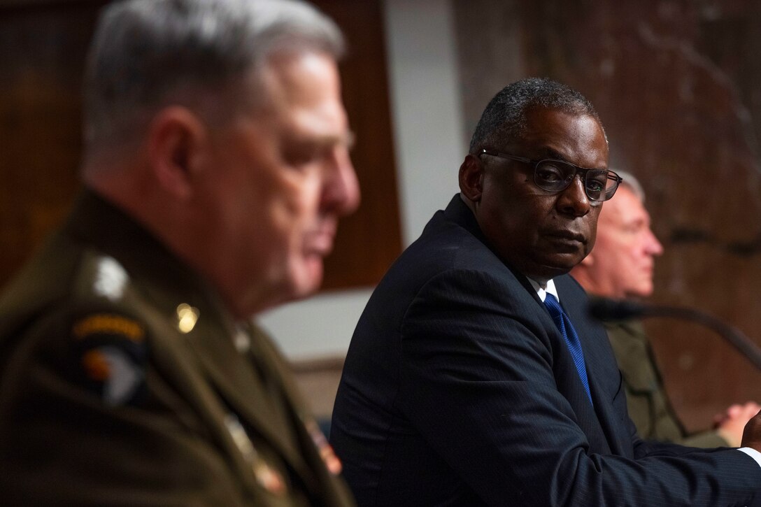 Three men sit at a table.
