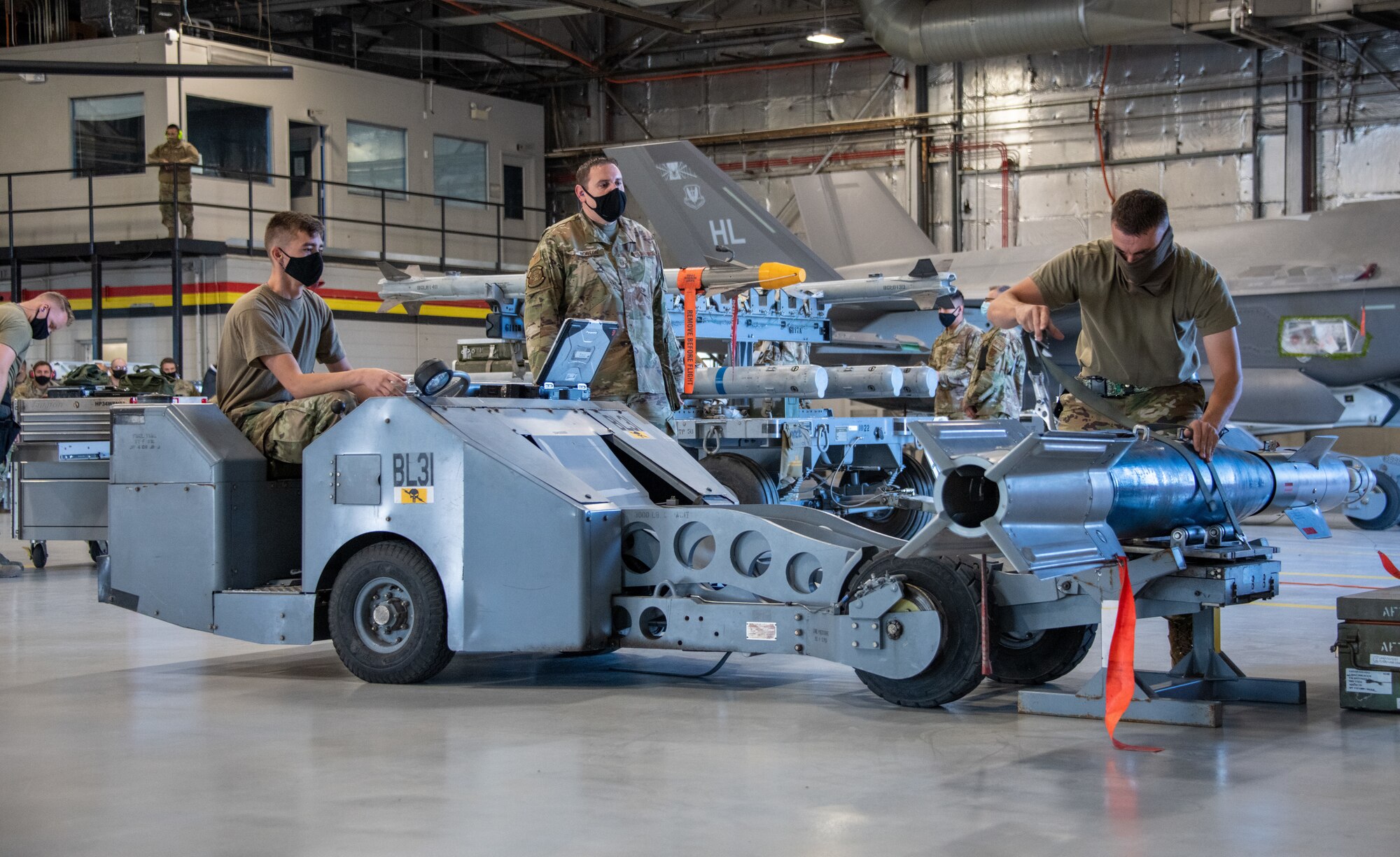 A judge watches two Airmen from the 419th Aircraft Maintenance Squadron load and secure an unarmed GBU-12 Pave Way to a bomb lift during a weapons load competition at Hill Air Force Base, Utah on Sept. 24, 2021. The quarterly competition focuses on speed, accuracy, and safety, ensuring standard loading procedures and proficiency across the wings. (U.S. Air Force photo by Senior Airman Erica Webster)