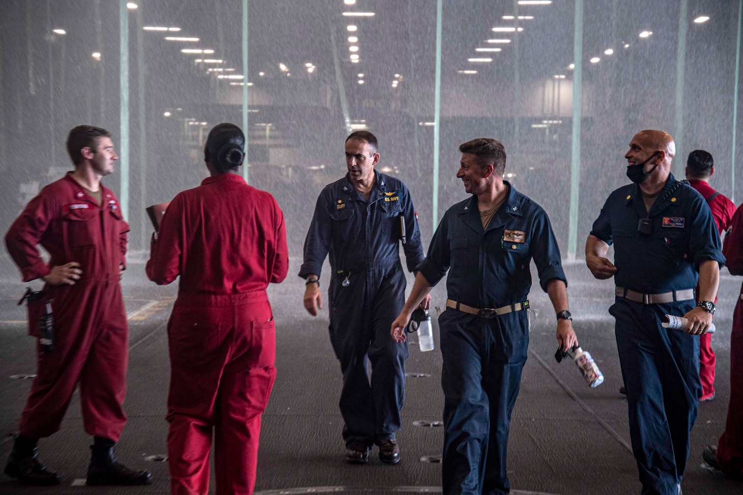 Capt. Gavin Duff, center, commanding officer of the Nimitz-class aircraft carrier USS Harry S. Truman (CVN 75), and Capt. Shane Marchesi, Truman's executive officer, speak with Sailors during an operational test of the aqueous film-forming foam sprinkler system in Truman's hangar bay.