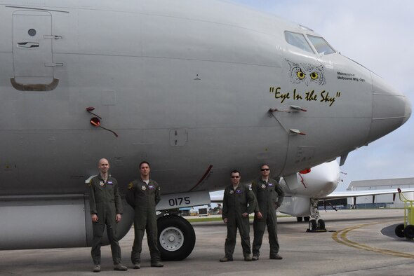 Photo shows four uniformed men standing in front of large aircraft.