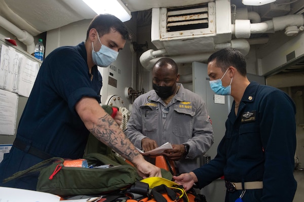 Hospital Corpsman 3rd Class Charles Connors, left, from Carmel, Indiana, Lt. Brandon Lavender, center, from Tuscaloosa, Alabama, an inspector assigned to the Board of Inspection and Survey (INSURV), and Chief Hospital Corpsman Joe McBride, right, from Forrest Grove, Oregon, inspect a gun bag aboard the Nimitz-class aircraft carrier USS Harry S. Truman (CVN 75).