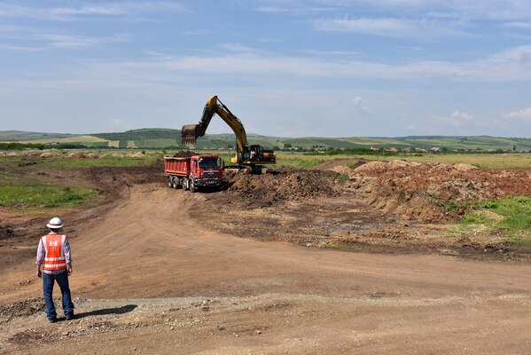 U.S. Army Corps of Engineers, Europe District Project Engineer Kevin Gray keeps an eye on contractors loading soil as part of ongoing construction activities at Campia Turzii Air Base, Romania, during a site visit June 22, 2021. The U.S. Army Corps of Engineers is managing a growing construction mission at Campia Turzii that is part of the European Deterrence Initiative, being implemented by the U.S. European Command. The EDI enables the United States to enhance the U.S. deterrence posture, increase the readiness and responsiveness of U.S. forces in Europe, support the collective defense and security of NATO allies, and bolster the security and capacity of U.S. allies and partners.