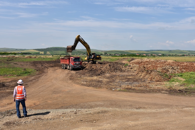 U.S. Army Corps of Engineers, Europe District Project Engineer Kevin Gray keeps an eye on contractors loading soil as part of ongoing construction activities at Campia Turzii Air Base, Romania, during a site visit June 22, 2021. The U.S. Army Corps of Engineers is managing a growing construction mission at Campia Turzii that is part of the European Deterrence Initiative, being implemented by the U.S. European Command. The EDI enables the United States to enhance the U.S. deterrence posture, increase the readiness and responsiveness of U.S. forces in Europe, support the collective defense and security of NATO allies, and bolster the security and capacity of U.S. allies and partners.