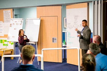 U.S. Air Force Lt. Col. Hans Winkler, center right, 423rd Civil Engineering Squadron commander, briefs Emergency Management professionals during an Operational Planning team meeting at RAF Alconbury, England, Sept. 28, 2021. The meeting was intended to provide a foundation and framework for command & control operations and reporting within the 501st Combat Support Wing as well as critical communication connection to mission partners. During the meeting EM members worked together to develop an organizational C2 process that establishes a defined wing-wide network across all 501 CSW installations and organizations including mission partners and geographically separated units. (U.S. Air Force photo by Senior Airman Eugene Oliver)