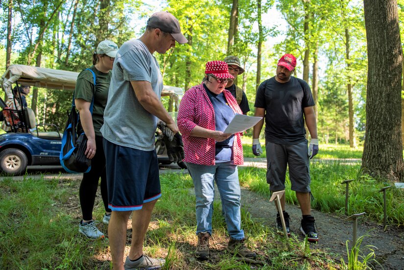 Pennsylvania Air National Guardsmen assigned to the 111th Attack Wing headquartered in Horsham, Pennsylvania, listen to Deb Woolson, Friends of Medal of Honor Grove Volunteer Director, as she gives instructions for the memorial renovations at the Medal of Honor Grove, Freedoms Foundation, Valley Forge, Pennsylvania, June 16, 2021. The 111th volunteered to help the Friends of the Medal of Honor Grove, an all-volunteer group that maintains the living memorial, to clean up and renovate Medal of Honor Recipient Memorials that needed tending to after COVID-19 precautions restricted volunteers from working there.
