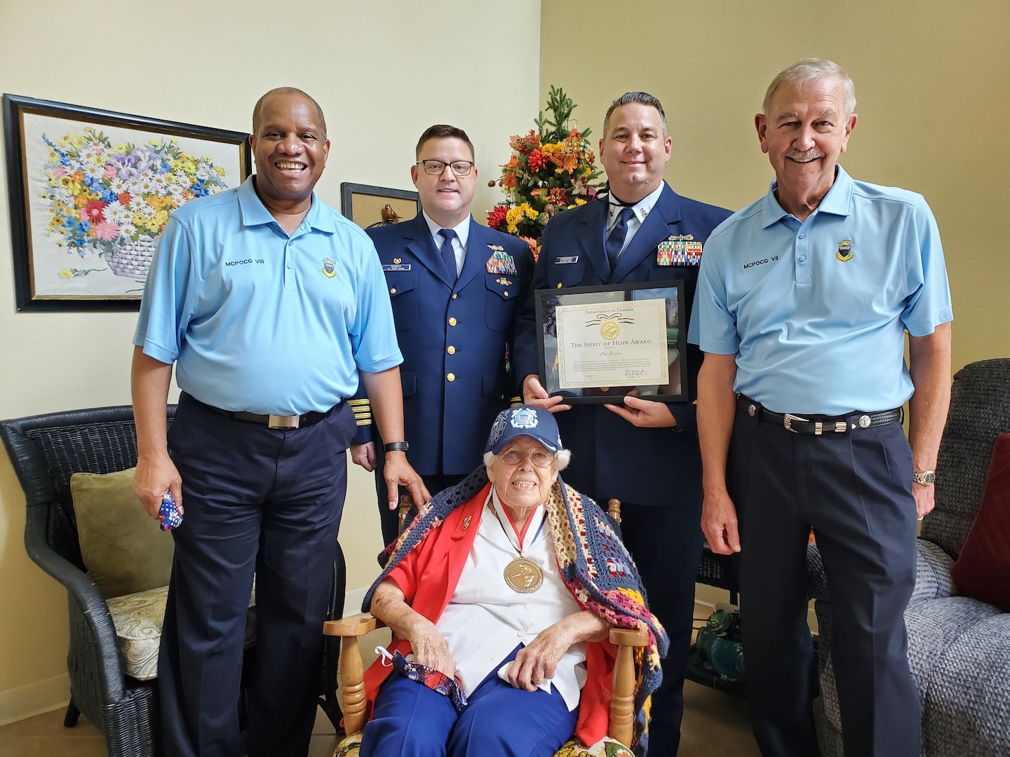 Lois Bouton, “The Coast Guard Lady,” is honored with the 2021 Spirit of Hope Award, Sept. 16, 2021, at Innisfree Senior Care Center, Rogers, Arkansas. The award is given to outstanding Americans whose patriotism and service epitomize courage, honor, duty, commitment, integrity, and selfless dedication. Photo by Coast Guard Auxiliarist Jesse Adams. 
(Left to Right) retired Master Chief Petty Officer Vince Patton, eighth MCPOCG, Capt. Ryan Rhodes, commander Sector Lower Mississippi River, Senior Chief Petty Officer Jameson Hannaman, Sector command senior chie, and retired Master Chief Petty Officer Rick Trent, seventh MCPOCG (Center) Master Chief Petty Officer Lois Bouton.