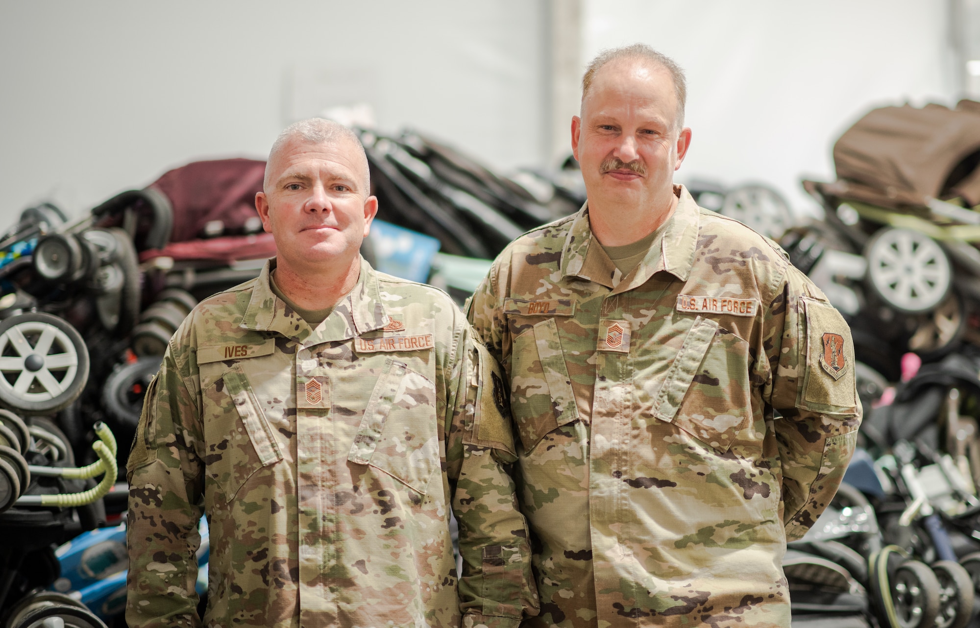U.S. Air Force Chief Master Sgt. Marvin Boyd, Washington Air National Guard Command Chief, and Chief Master Sgt. Brandon Ives, 141st Air Refueling Wing command chief, pose for a photo in front of a large donation of strollers at Liberty Village, Joint Base McGuire-Dix-Lakehurst, New Jersey, Sept. 27, 2021. Boyd handed over the senior enlisted leader of Village Three position to Ives. The Department of Defense, through U.S. Northern Command, and in support of the Department of Homeland Security, is providing transportation, temporary housing, medical screening, and general support for at least 50,000 Afghan evacuees at suitable facilities, in permanent or temporary structures, as quickly as possible. This initiative provides Afghan personnel essential support at secure locations outside Afghanistan. (U.S. Air Force photo by Capt. Francine St Laurent)