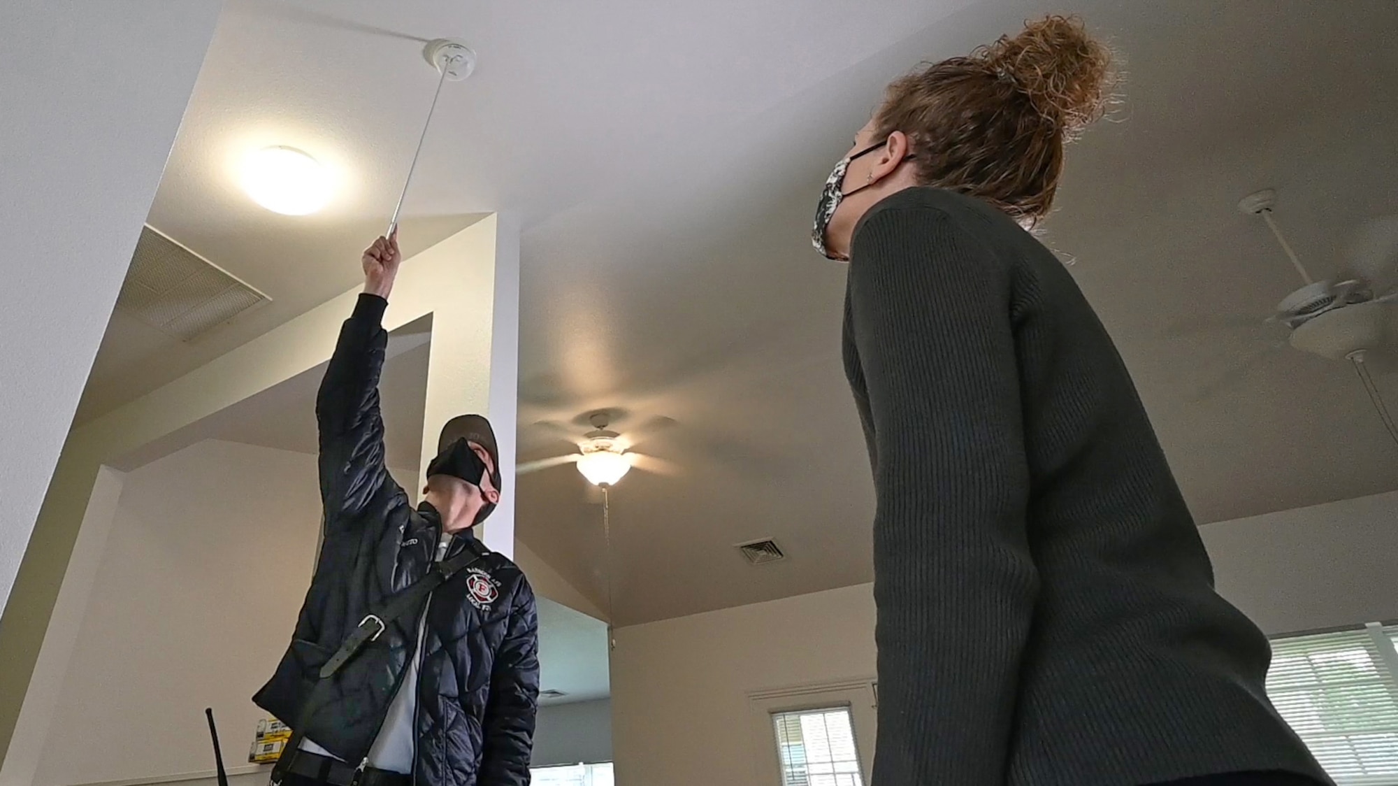 Hanscom Fire Lt. Casey Videtto tests a smoke alarm while LauraLee Morris, Hanscom’s resident advocate, looks on.