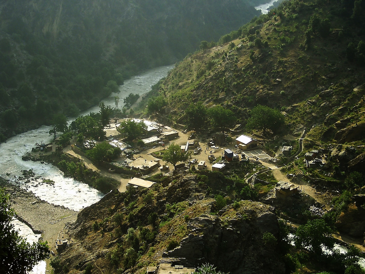 A small military outpost sits in a valley near a river.