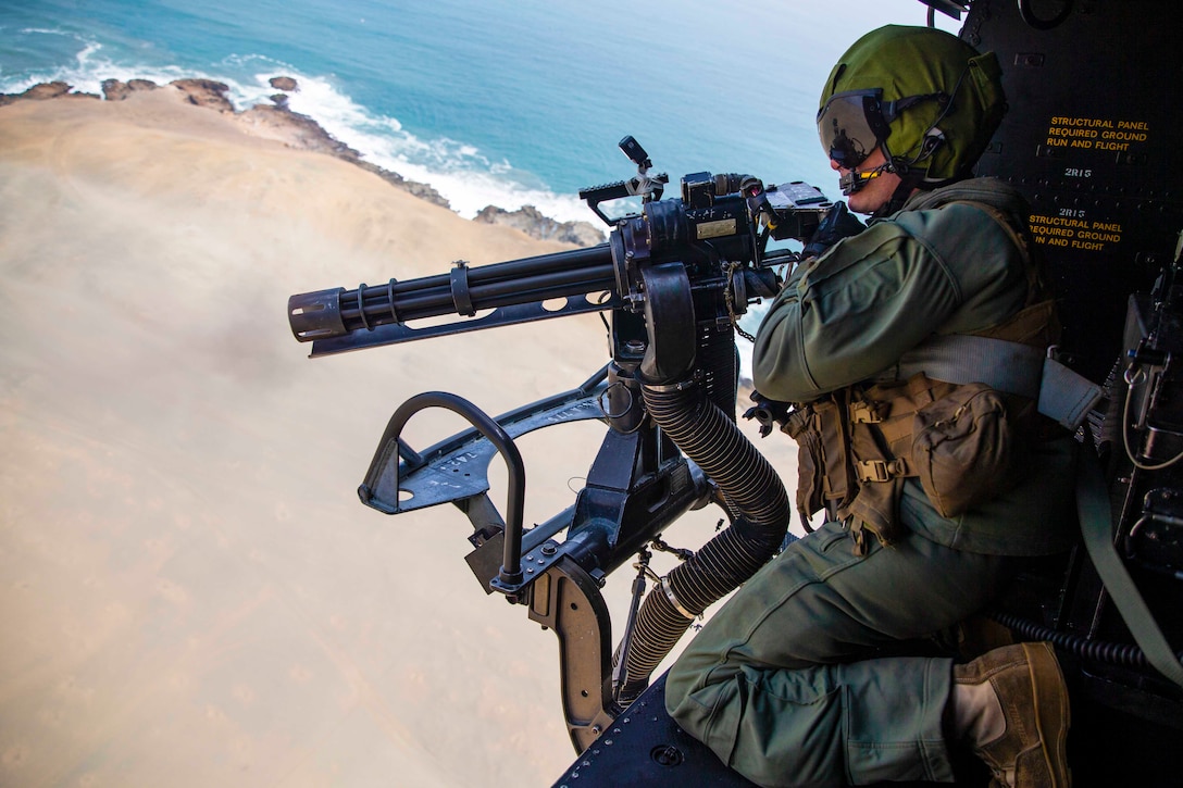 A Marine fires a weapon from an airborne aircraft.