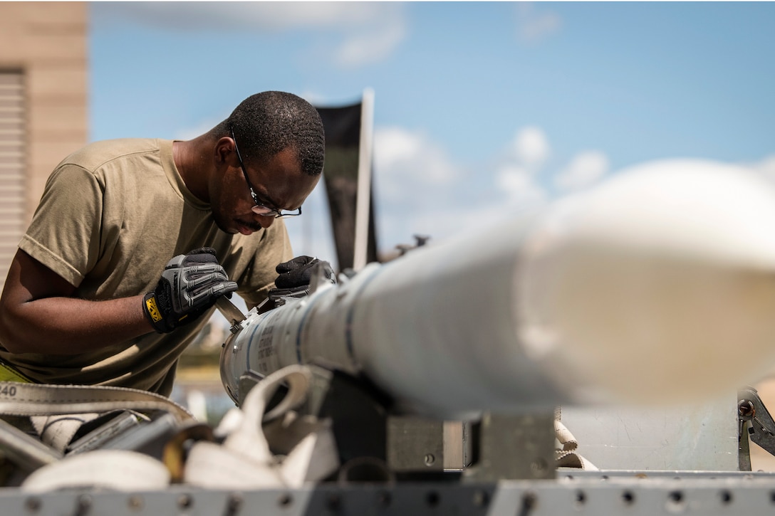 An airman performs maintenance on a missile during a competition.
