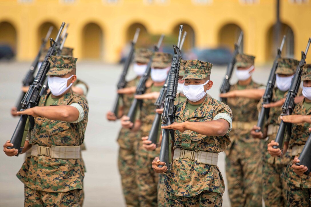 Marines stand in formation while holding weapons.