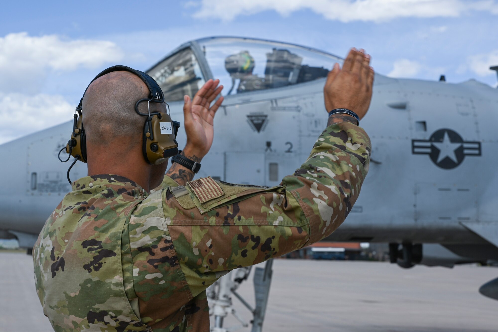 A photo of an Airman marshalling a jet