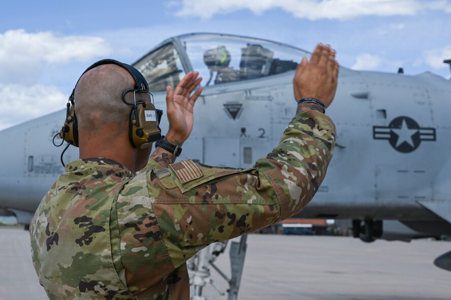 A photo of an Airman marshalling a jet