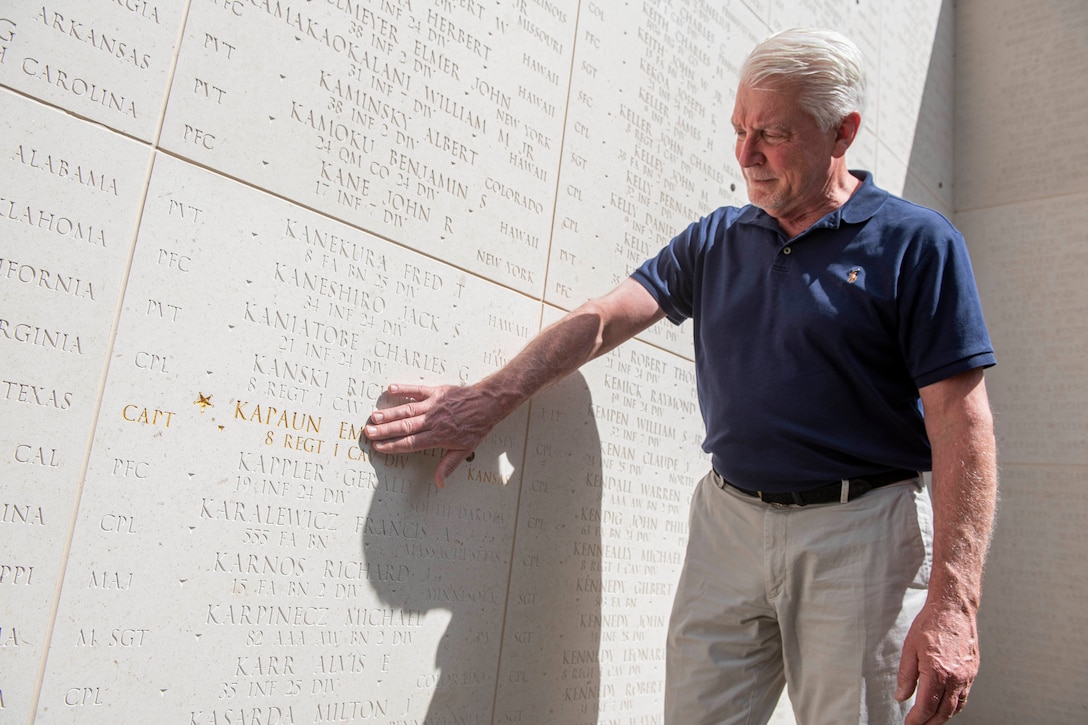 A man touches a memorial wall.