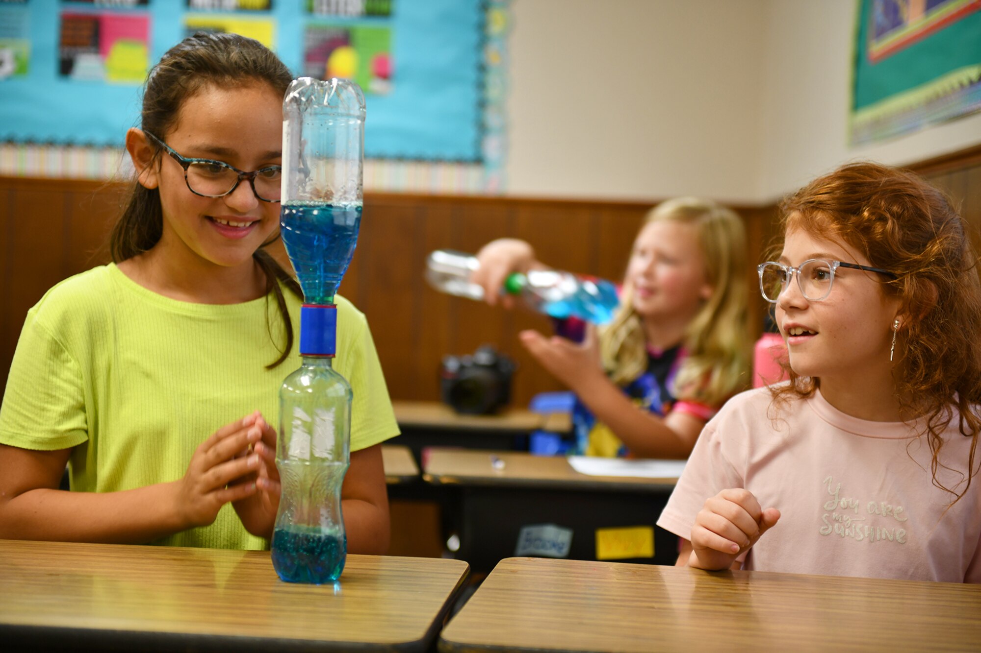Lilly Weston (left) and Tessa Mary (right) 4th grade students at Navajo Elementary School watch a water tornado in a bottle they created with plastic bottles, water, glitter and food coloring  in Altus, Oklahoma, Sep. 28, 2021. The team was able to educate students on the dangers of disasters and what they can do in the event that one strikes. (U.S. Air Force photo by Tech. Sgt. Robert Sizelove)