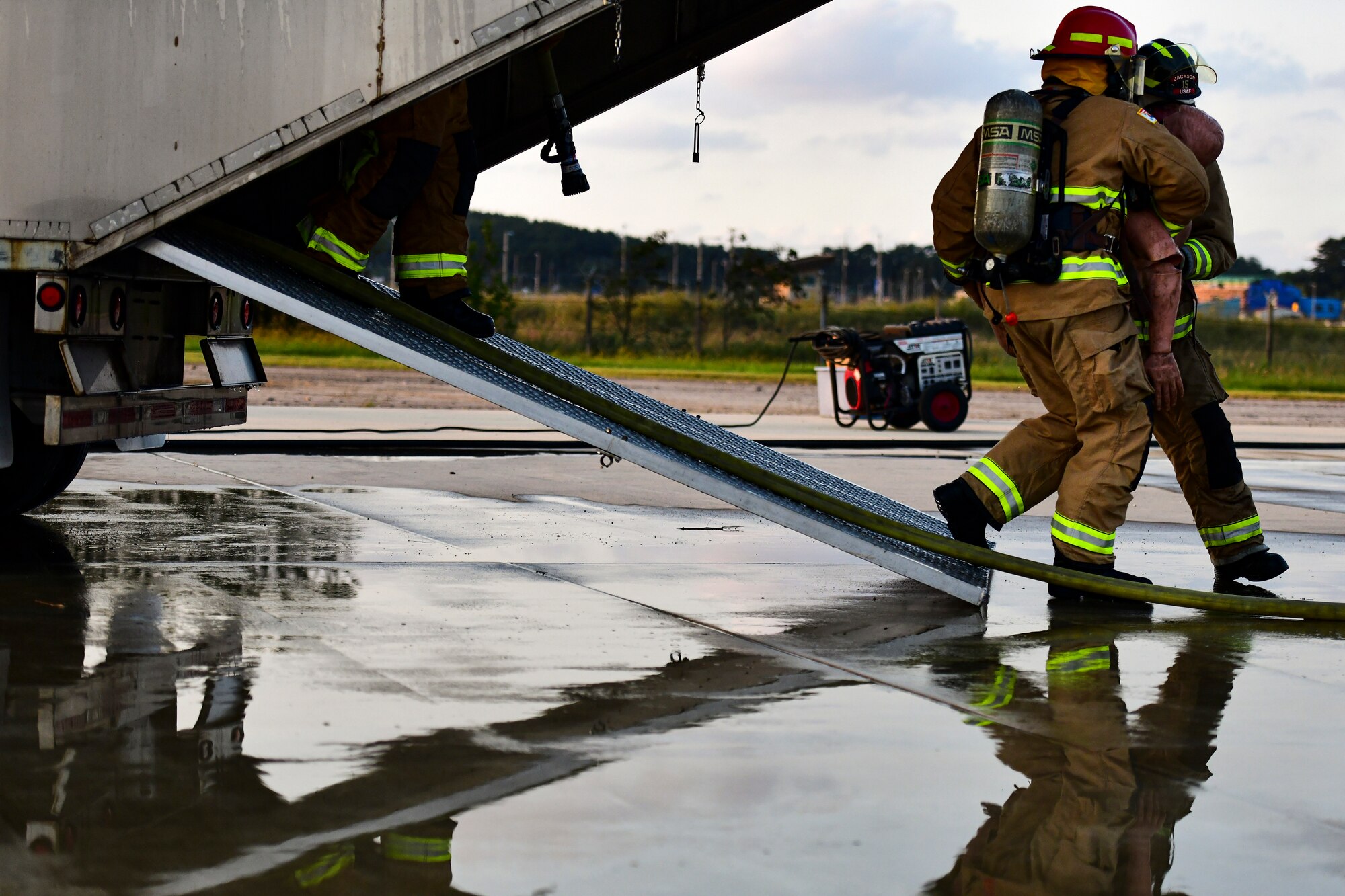 Airmen carry a simulated victim out of a simulated aircraft fire.