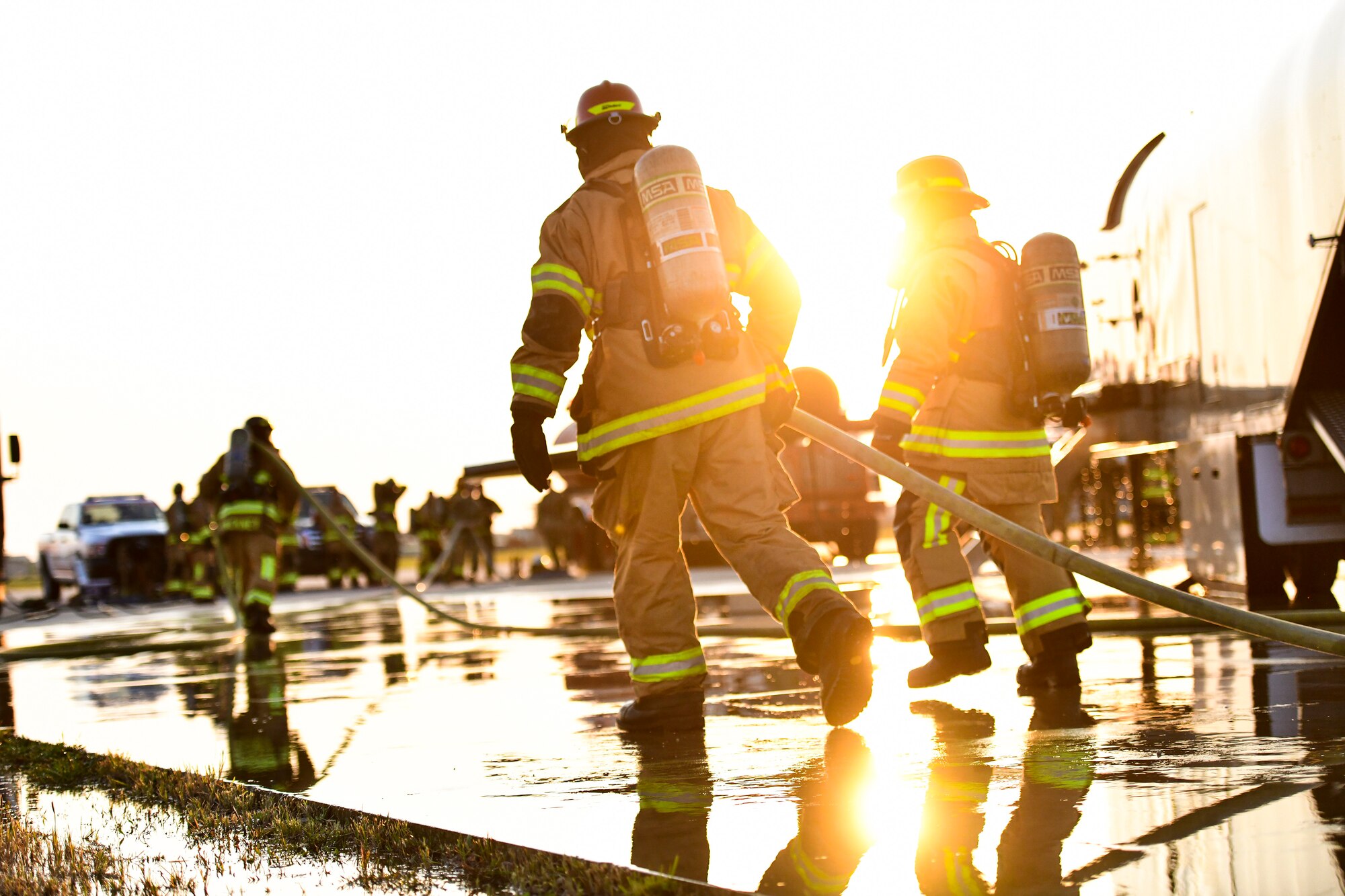 Firefighters carry a water hose.