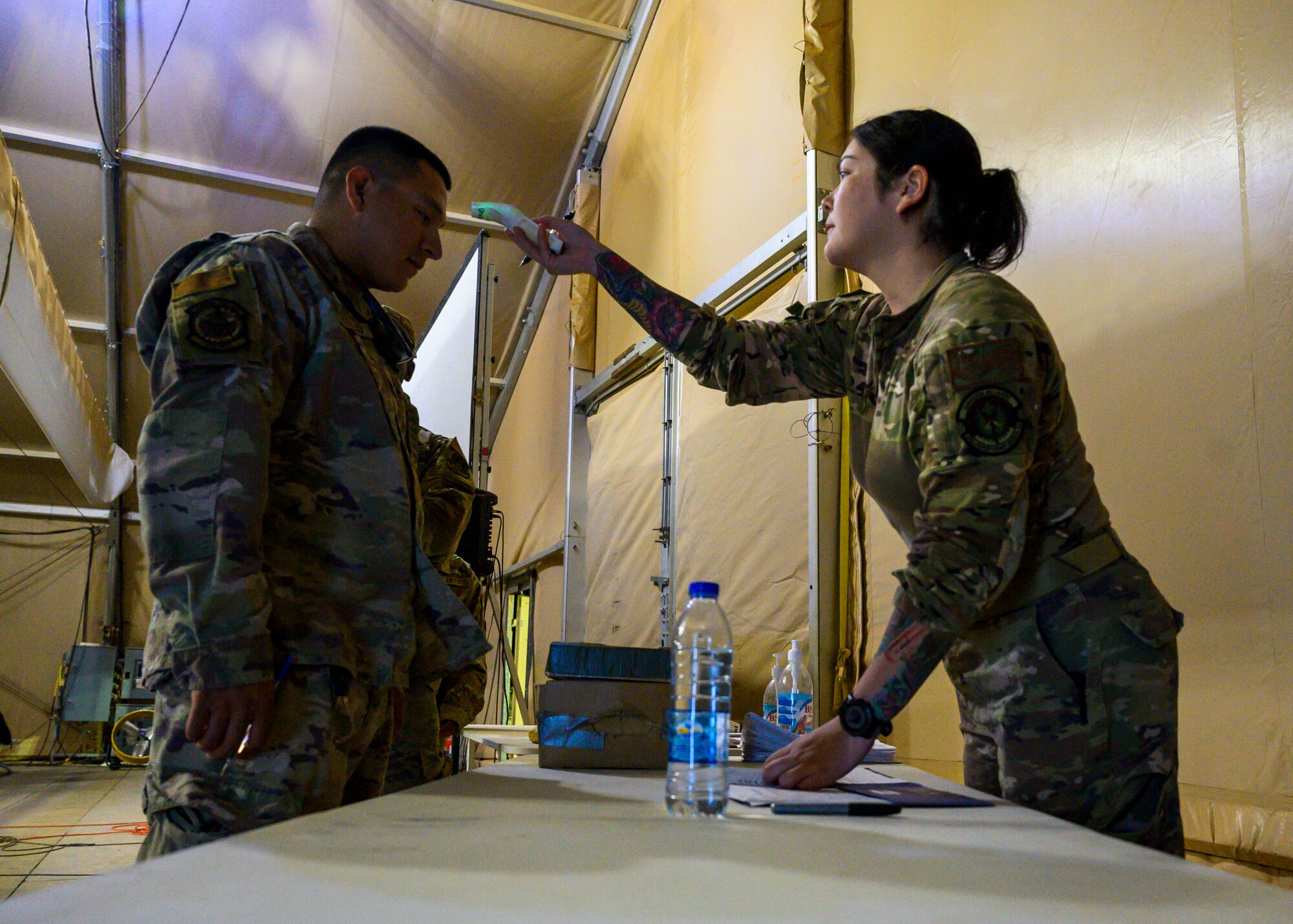 U.S. Air Force personnel perform a temperature check as part of a medical screening for members forward deploying to Al Udeid Air Base, Qatar, from Prince Sultan Air Base, Kingdom of Saudi Arabia, Aug. 20, 2021. The 378th Air Expeditionary Wing provided air support, logistics, manpower and resources to U.S. Air Forces Central in support of the evacuation of American citizens, special immigrant visa applicants and other at-risk individuals from Afghanistan. (U.S. Air Force photo by Senior Airman Samuel Earick)