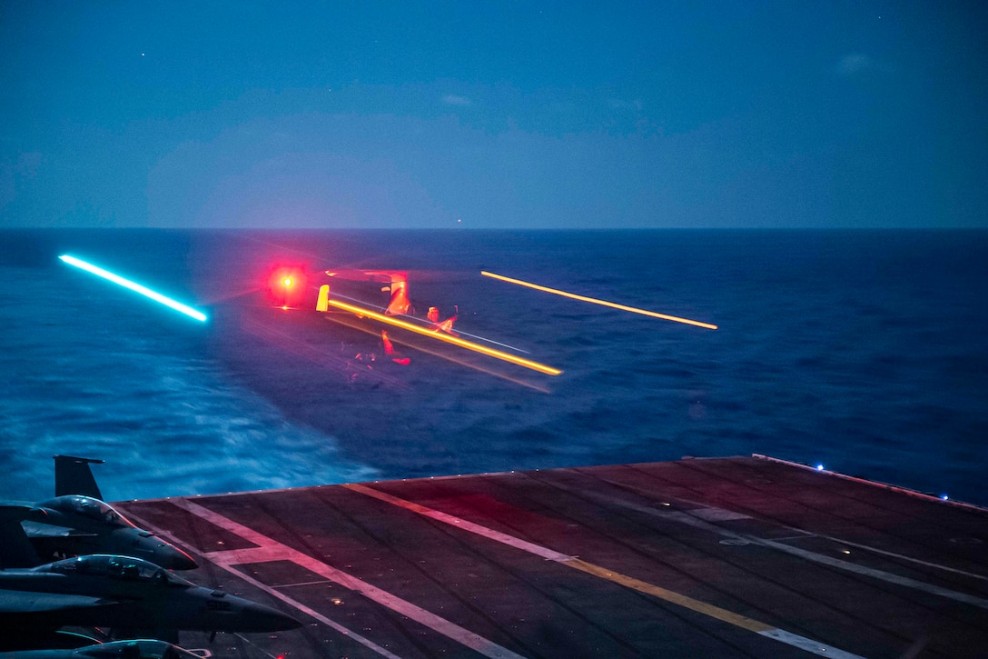 The lights from a military aircraft are seen at night.