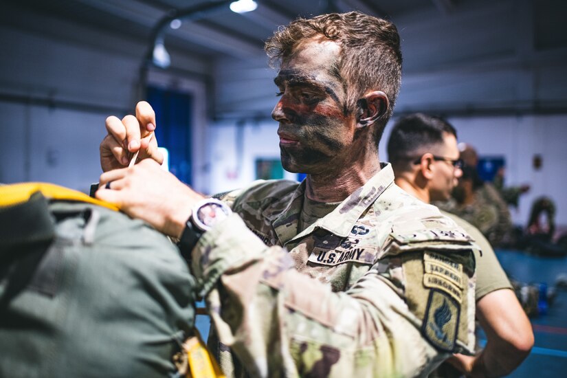 A soldier examines his parachute.