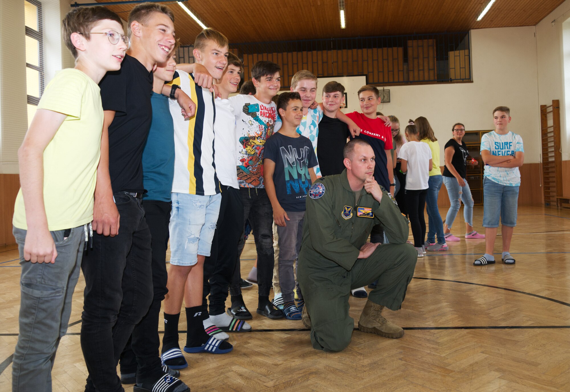 An Airman kneels in a photo with a group of children.