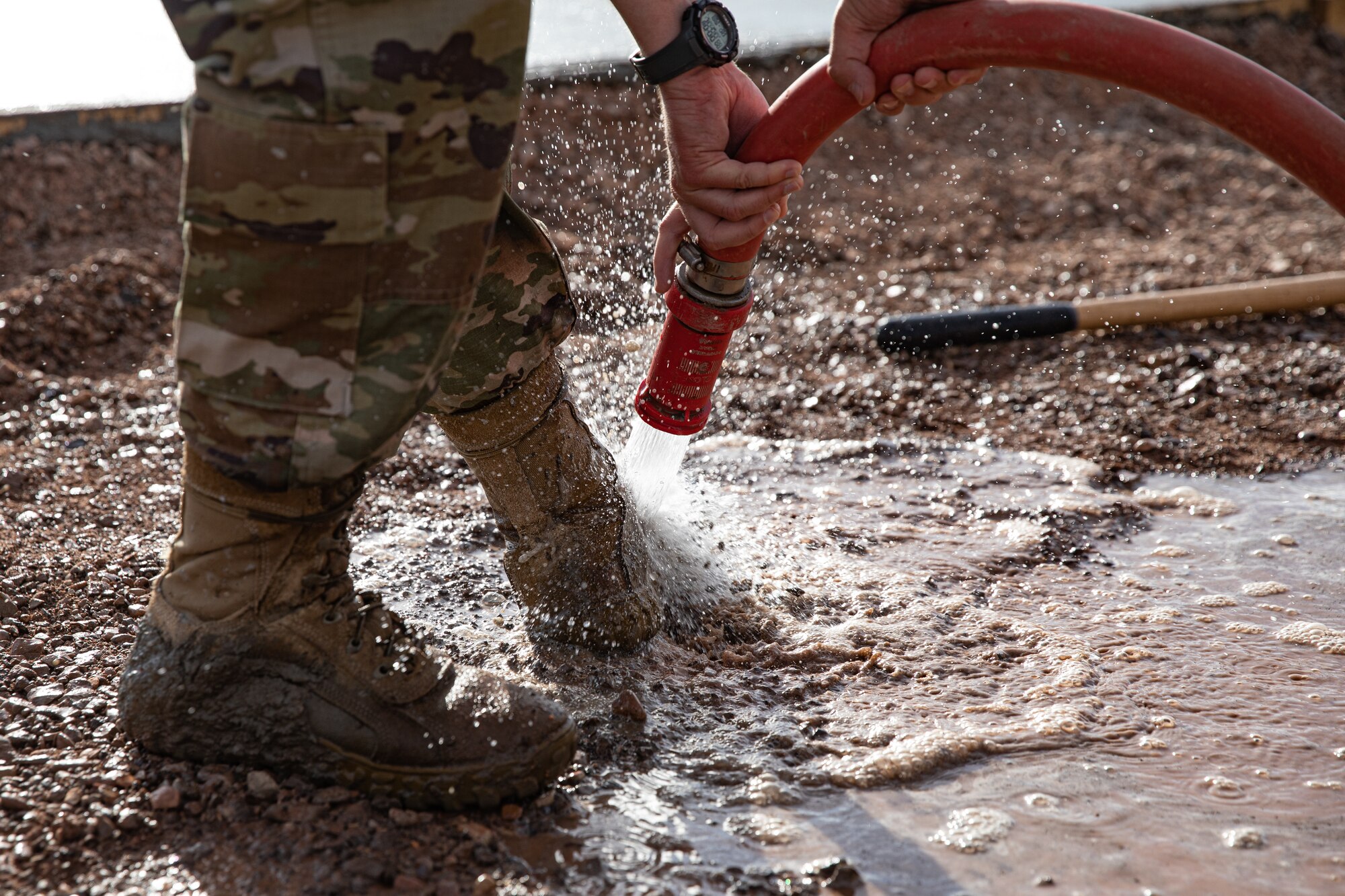 An Airman assigned to Task Force-Holloman cleans off their boots after laying down fresh concrete that will become a recreational area for Afghan evacuees on Holloman Air Force Base, New Mexico, Sept. 23, 2021. The Department of Defense, through the U.S. Northern Command, and in support of the Department of State and Department of Homeland Security, is providing transportation, temporary housing, medical screening, and general support for at least 50,000 Afghan evacuees at suitable facilities, in permanent or temporary structures, as quickly as possible. This initiative provides Afghan evacuees essential support at secure locations outside Afghanistan.(U.S. Army photo by Spc. Nicholas Goodman)