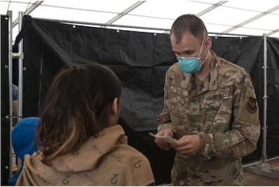 U.S. Air Force Tech. Sgt. Evans, 86th Operational Medical Readiness Squadron mental health noncommissioned officer in charge, assists an evacuee during a measles, mumps and rubella vaccination program at Ramstein Air Base, Sept. 17, 2021. The OMRS mental health flight has been catering to the mental health of Airmen and the evacuees during evacuation operations. Evacuees receive support such as temporary lodging, food and water and access to medical care at Ramstein Air Base while awaiting transportation to other transient locations. (U.S. Air Force photo by Senior Airman Milton Hamilton)