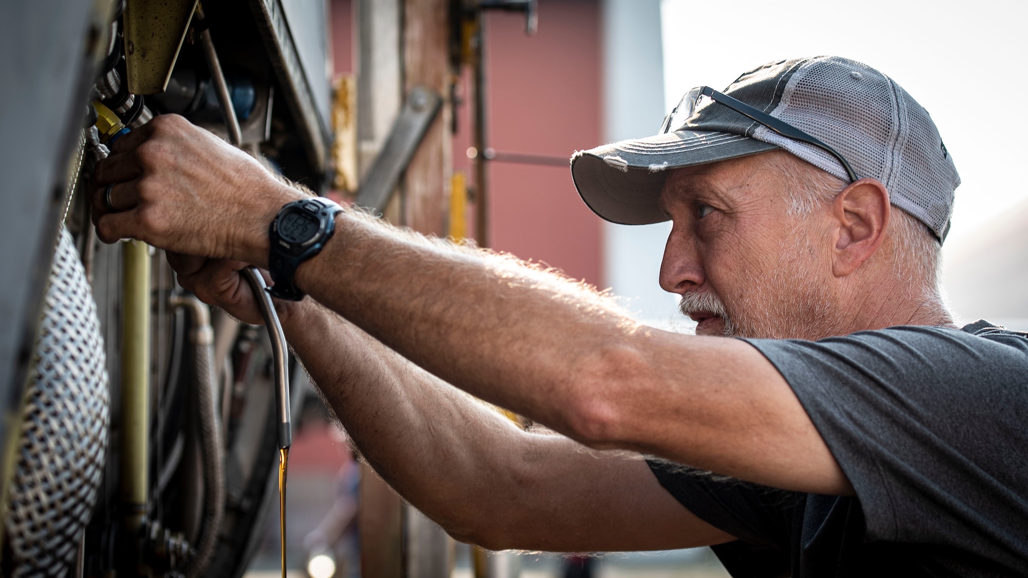 Photo of a contractor draining oil from a C-130 Hercules engine.