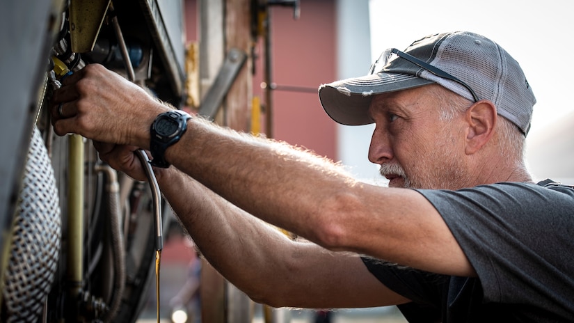 Photo of a contractor draining oil from a C-130 Hercules engine.