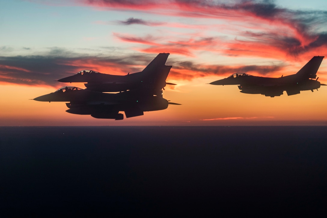 Three aircraft fly as the sun sets.