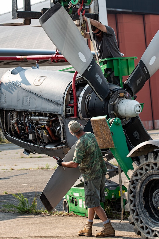 Photo of contractors adjusting a C-130 Hercules engine.