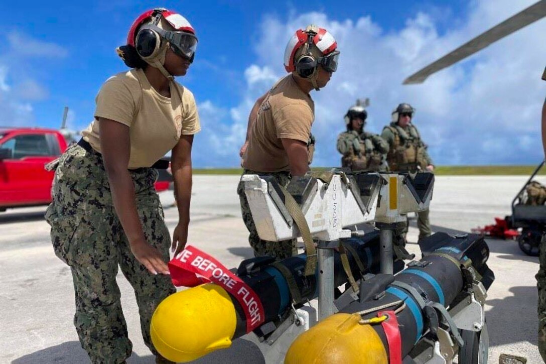 Two sailors prepare to move a missile.