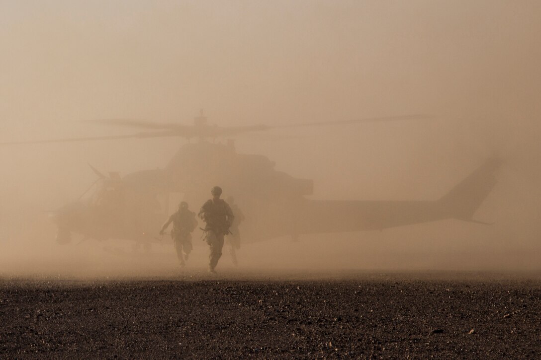 Marines and a helicopter are seen during a dust storm.