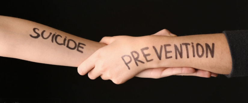 Suicide prevention logo of five figures of people holding hands.