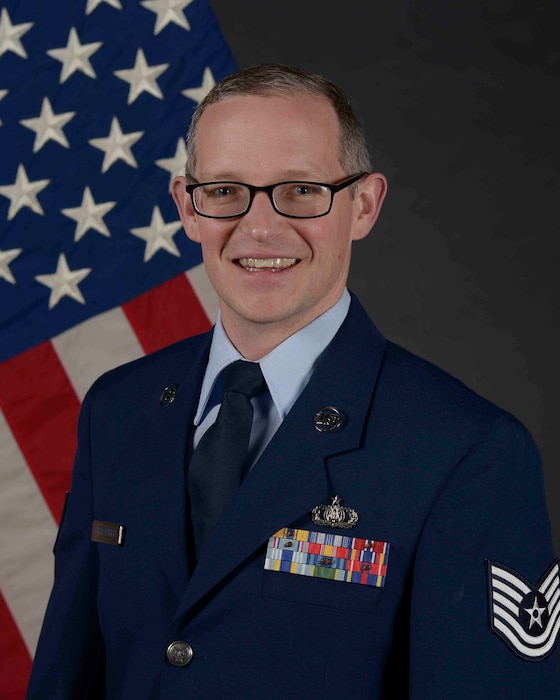 Airman posed in front of a flag
