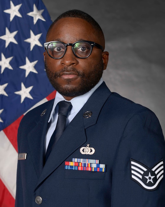 Airman posed in front of a flag