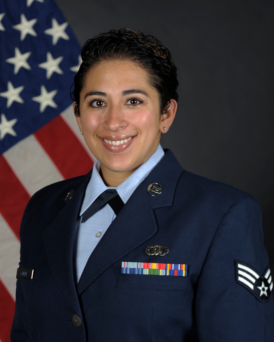 airman posed in front of a flag