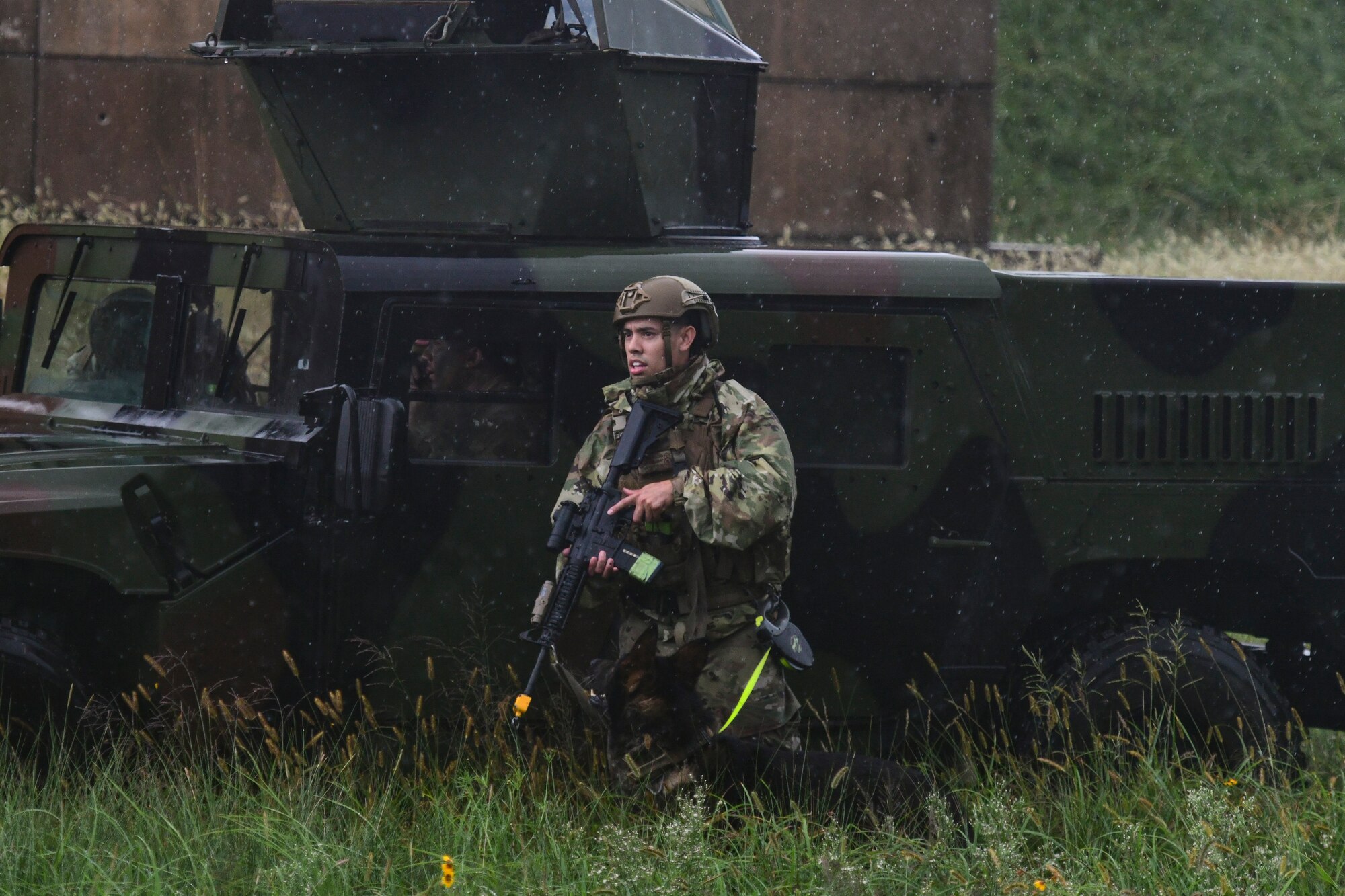 An Airman searches a scene with a Humvee.