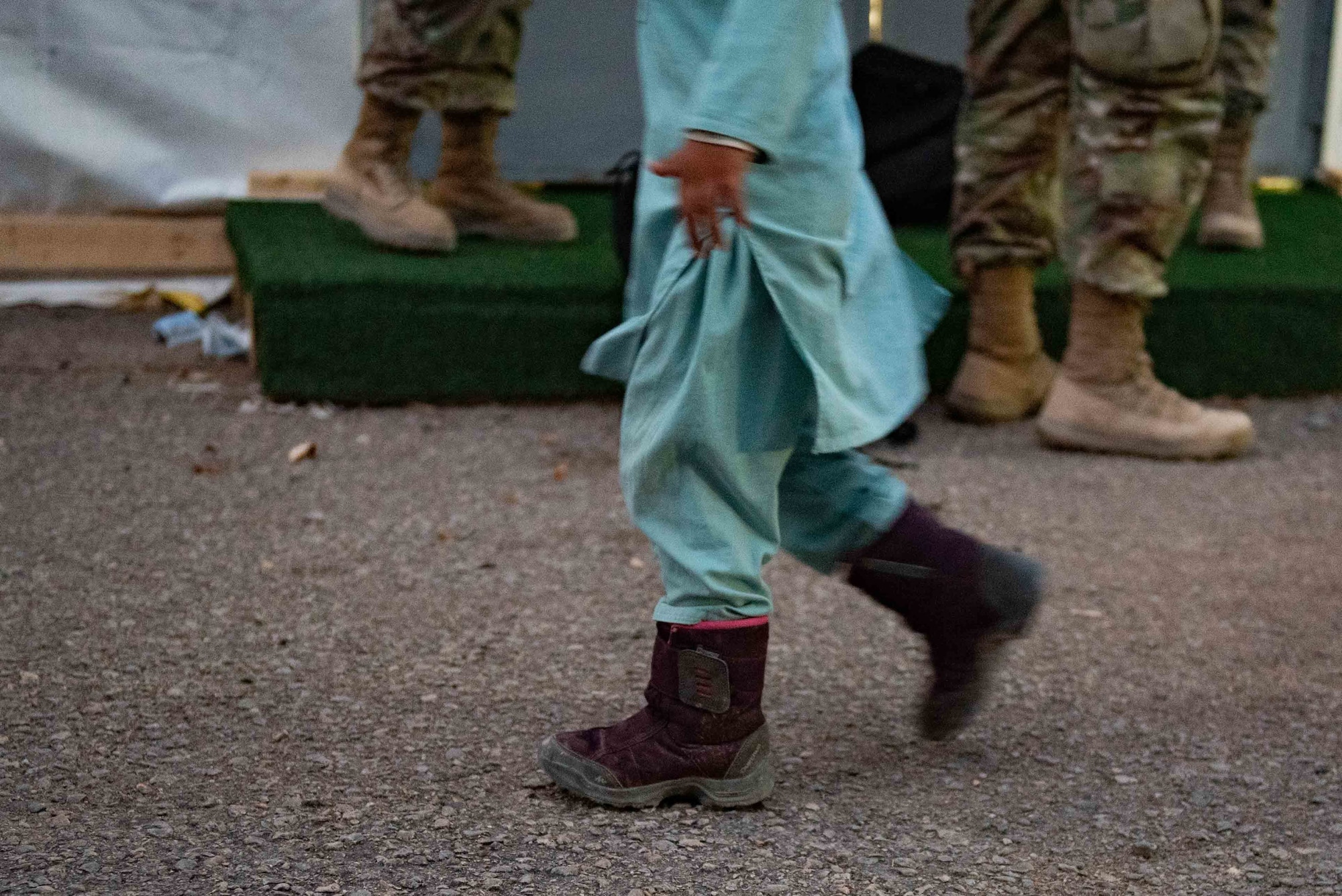 An Afghan child walks with his family to start the resettlement process on Holloman Air Force Base, New Mexico, Sept. 28, 2021. The Department of Defense, through U.S. Northern Command, and in support of the Department of State and Department of Homeland Security, is providing transportation, temporary housing, medical screening, and general support for at least 50,000 Afghan evacuees at suitable facilities, in permanent or temporary structures, as quickly as possible. This initiative provides Afghan evacuees essential support at secure locations outside Afghanistan. (U.S. Air Force photo by Staff Sgt. Kenneth Boyton)
