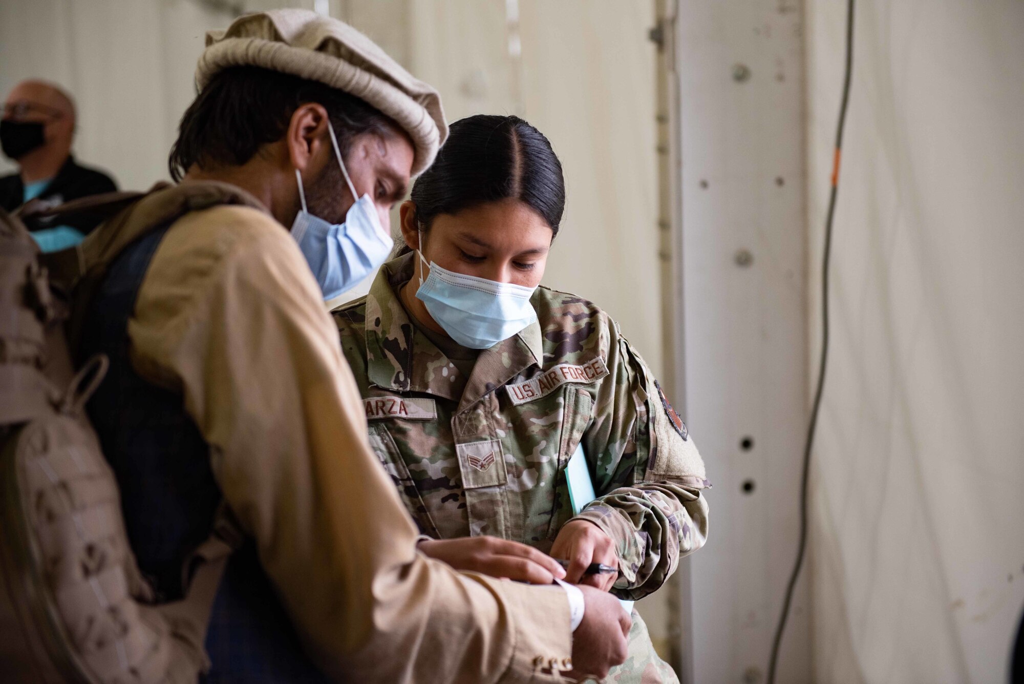 Senior Airman Lesley Garza, Task Force-Holloman village personnel support for contingency operations supervisor, deployed from Randolph Air Force Base, Texas, helps outprocess Afghan evacuees before they depart Holloman Air Force Base, New Mexico, Sept. 28, 2021. The Department of Defense, through U.S. Northern Command, and in support of the Department of State and Department of Homeland Security, is providing transportation, temporary housing, medical screening, and general support for at least 50,000 Afghan evacuees at suitable facilities, in permanent or temporary structures, as quickly as possible. This initiative provides Afghan evacuees essential support at secure locations outside Afghanistan. (U.S. Air Force photo by Staff Sgt. Kenneth Boyton)