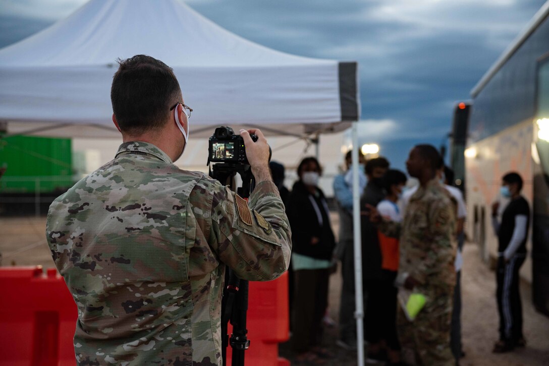 Senior Airman Skyler Combs, Task Force-Holloman public affairs specialist, deployed from McConnell Air Force Base, Kansas, documents Afghan families as they start the resettlement process on Holloman Air Force Base, New Mexico, Sept. 28, 2021. The Department of Defense, through U.S. Northern Command, and in support of the Department of State and Department of Homeland Security, is providing transportation, temporary housing, medical screening, and general support for at least 50,000 Afghan evacuees at suitable facilities, in permanent or temporary structures, as quickly as possible. This initiative provides Afghan evacuees essential support at secure locations outside Afghanistan. (U.S. Air Force photo by Staff Sgt. Kenneth Boyton)