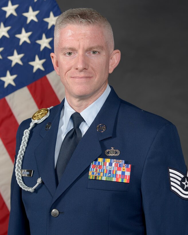 Airman posed in front of a flag