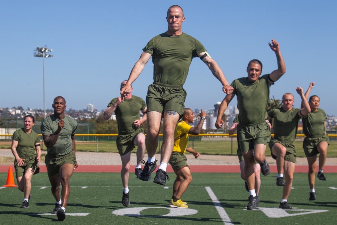 A group of Marine Corps recruits run and jump toward the camera.