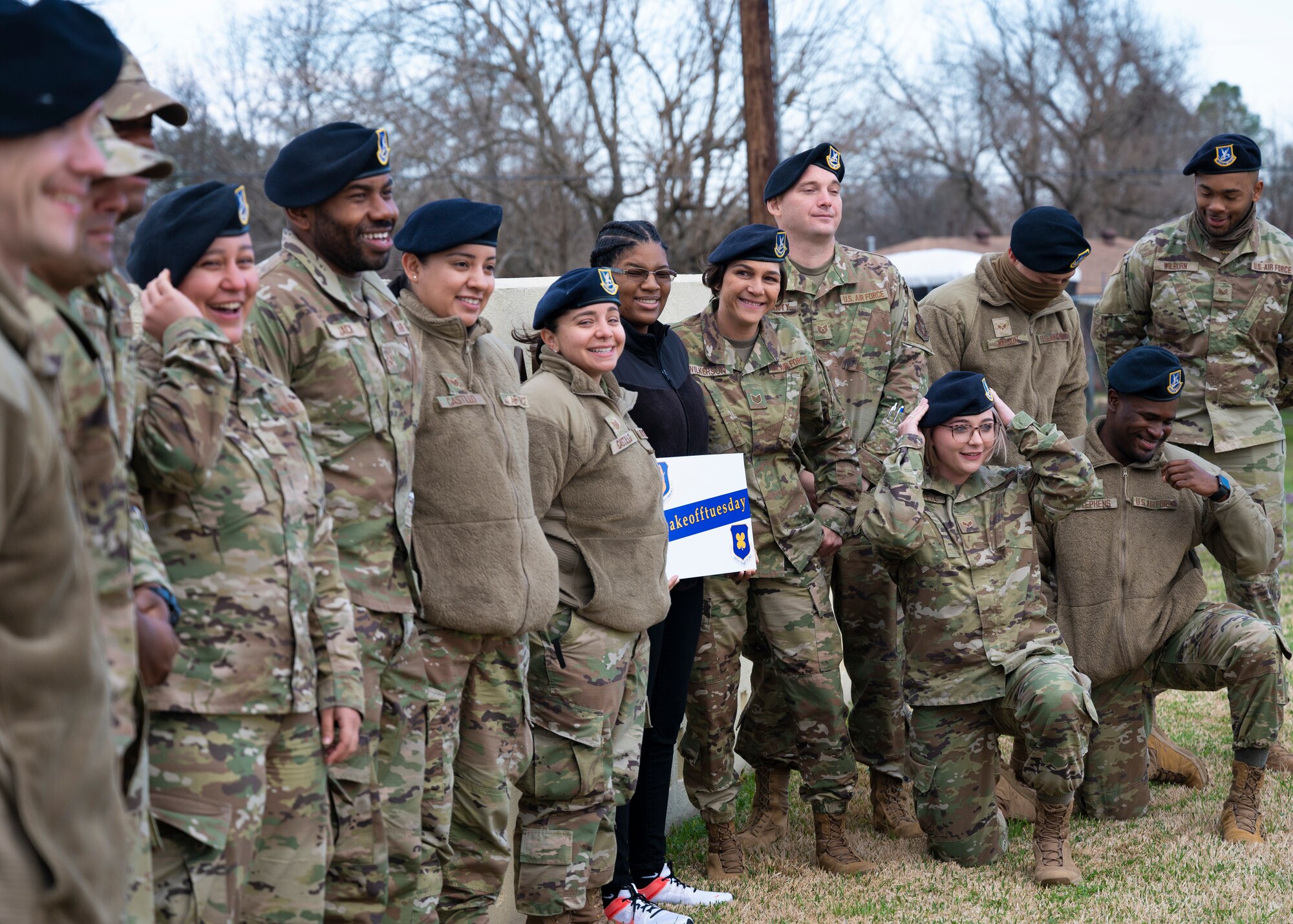 Fifteen people stand outside smiling at the camera.