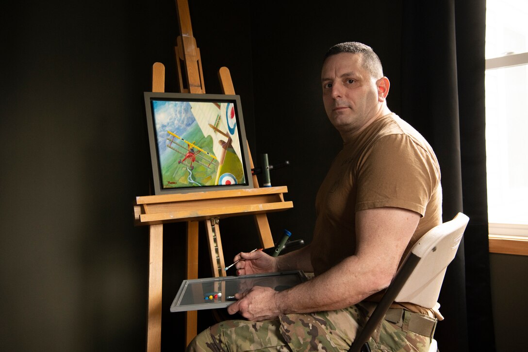 U.S. Army Staff Sgt. Stephen Foster displays his painting at his house near Grand Ledge Aviation Readiness Center, Grand Ledge, Michigan, Mar. 24, 2022. Foster’s latest painting, an acrylic painting titled “High Maintenance”, took first place in the acrylic painting category and was named Best in Show at the Battle Creek 2021 Veterans Creative Art Competition. (U.S. Air National Guard photo by Staff Sgt. Jacob Cessna)