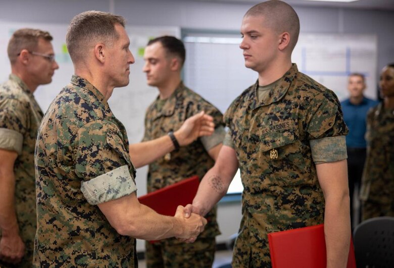 U.S. Marine Corps Col. George Markert, chief of staff with 2nd Marine Logistics Group, shakes hands with Cpl. Johnathan Ritter, an automotive maintenance technician with 2nd Maintenance Battalion, after he received a Navy and Marine Corps Achievement Medal at the II Marine Expeditionary Force (MEF) Innovation Campus during its grand opening on Camp Lejeune, North Carolina, April 1, 2022. The II MEF Innovation Campus is used to develop planning, cross-functional team building, creative problem-solving techniques, agile methodologies, idea generation frameworks, and 365/24/7 collaboration on a global scale in physical and virtual environments to maximize idea sharing, cross-domain collaboration, communication, and connectivity. (U.S. Marine Corps video created by Lance Cpl. Jessica J. Mazzamuto)