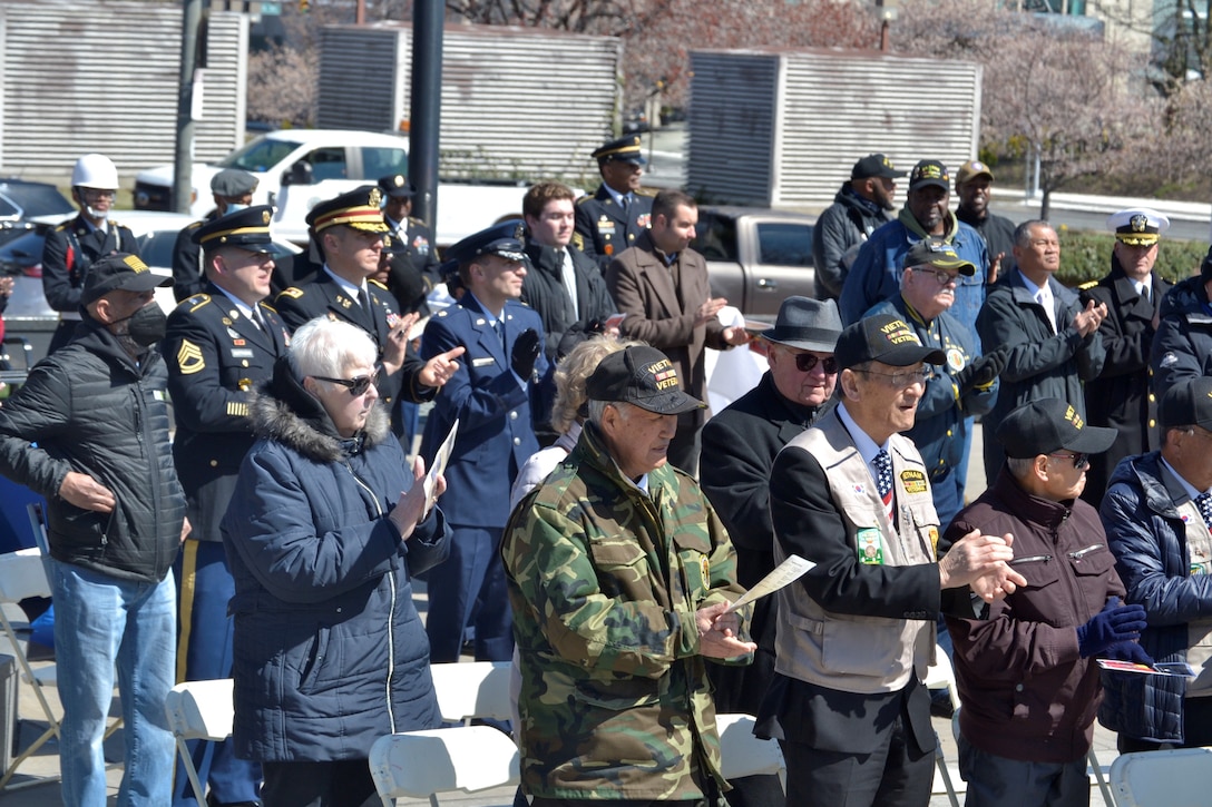 veterans, civilians and active duty military members stand and applaud