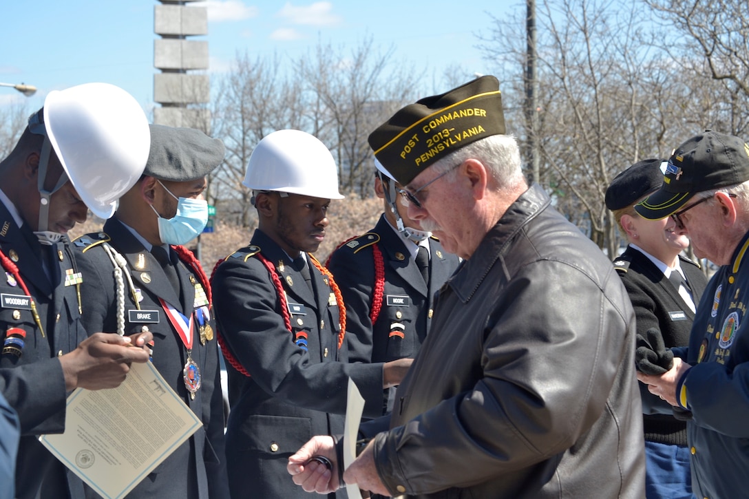 ROTC cadets present lapel pin and certificate to veteran man