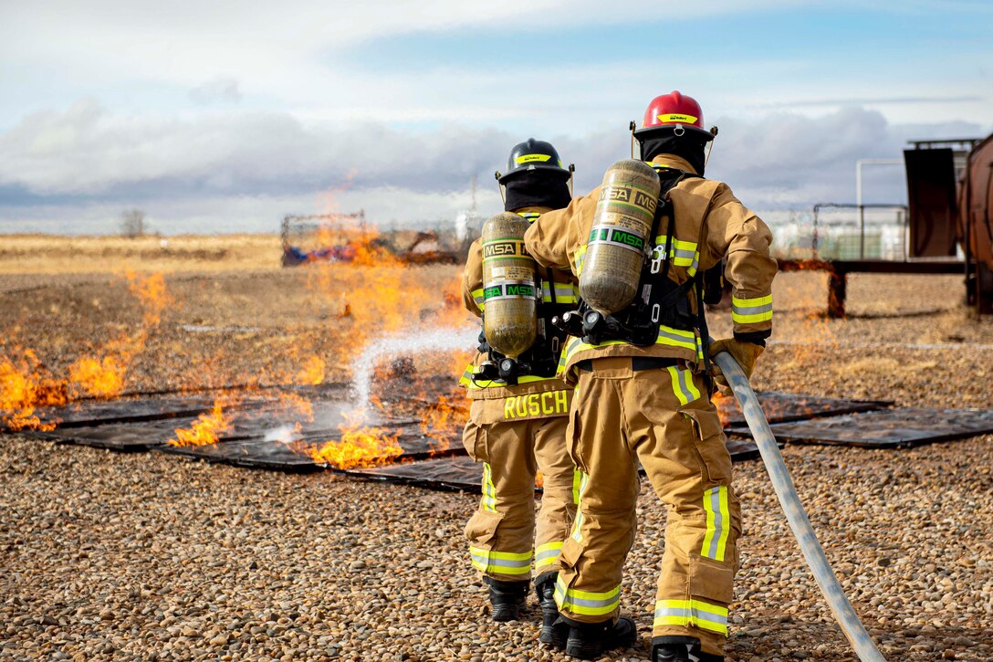 Two airmen put out a simulated fire during training.